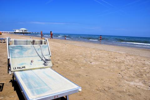 Das sommerliche Badevergnügen an der Adria: Am kilometerlangen Sandstrand reihen sich die Liegestühle und Sonnenschirme der Strandbäder eng an eng aneinander- (c) Gabi Vögele