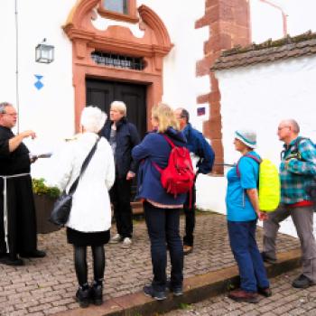 Bruder Tobias empfängt die Wandergruppe aus Gemünden am Barockkirchlein von Kloster Schönau - (c) Sabine Ludwig