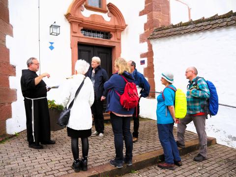 Bruder Tobias empfängt die Wandergruppe aus Gemünden am Barockkirchlein von Kloster Schönau - (c) Sabine Ludwig